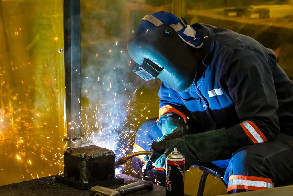 Male worker welding doing ship repairs